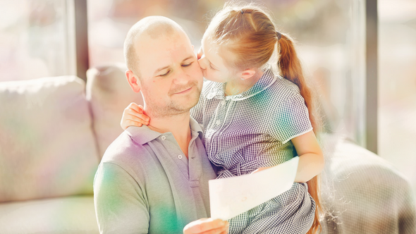 Vater, der von seiner Tochter einen Kuss auf die Wange bekommt